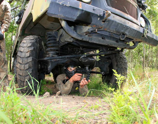 Joueur de Paintball caché sous un camion militaire de l'armée française